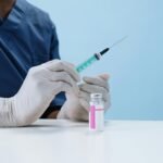 Close-up of a healthcare professional filling a syringe with vaccine from a vial.