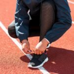 Close-up of an athlete tying sneakers on a track during the day. Perfect fit concept.